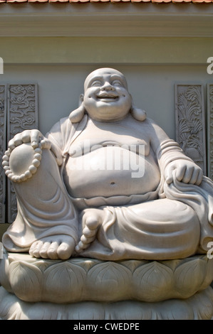Vertikale hautnah ein Fett laughing Buddha-Statue aus Marmor gehauen, an einem sonnigen Tag. Stockfoto