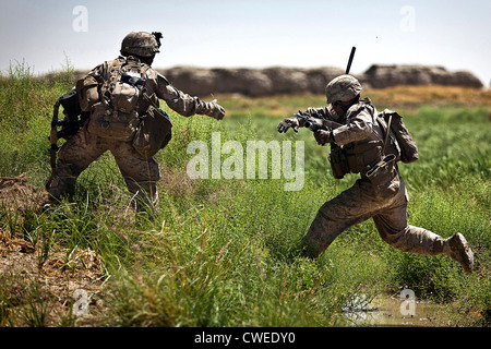 Ein US-Navy Petty Officer erstreckt sich eine helfende Hand auf ein US-Marine, wie er einen Stream während einer Sicherheitspatrouille 30. April 2012 in der Provinz Helmand, Afghanistan springt. Stockfoto