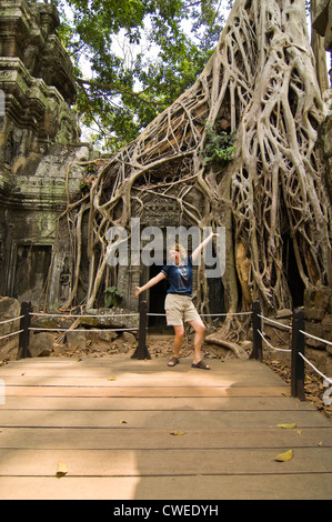 Vertikale Ansicht eines Touristen posiert auf einer der legendären Spots in Ta Prohm aka Rajavihara oder der Tomb Raider-Tempel in Ankor Thom. Stockfoto