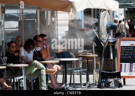 Kunden in einer Bar in die Place De La Comedie in Montpellier abkühlen vor eine große Fangemeinde mit einem kühlenden Nebel der Wasserstrahl Stockfoto