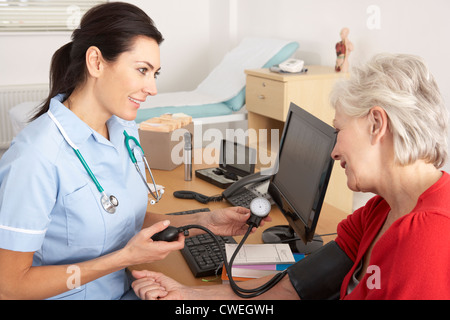 Britische Krankenschwester, die ältere Frau Blutdruckmessung Stockfoto