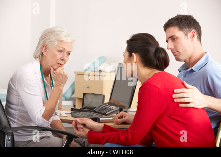 GP von Großbritannien im Gespräch mit ängstlich paar in der Chirurgie Stockfoto