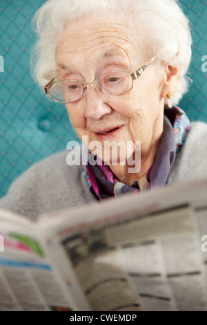 Entspannen im Sessel lesen Zeitung Senior Woman Stockfoto