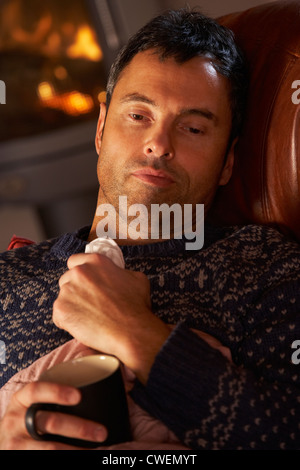 Kranker Mann mit kalten ruhen auf Sofa gemütliche Kaminfeuer Stockfoto