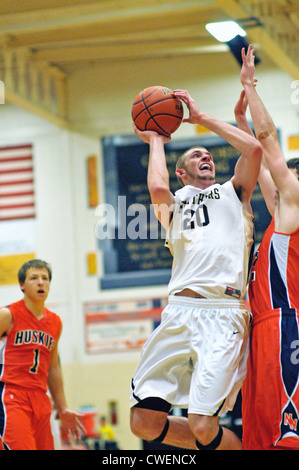 Basketball Spieler verlässt das Hartholz aus zu einem Schuss beim Umgang mit den in der Nähe der Verteidigung des Gegners High School Spiel erhalten. USA. Stockfoto