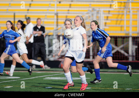Fußball Gymnasium Konkurrenten spielt den Ball aus ihrer Brust in einer Bemühung, sie in Richtung Boden abzulenken. Stockfoto