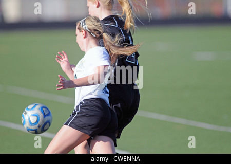 Fußball-Spieler drehen sich zusammen in Reaktion auf die Flugbahn des Balls während eines High-School-Fußballspiel. Stockfoto