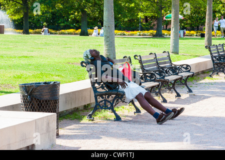 Mann schläft auf einer Parkbank Stockfoto