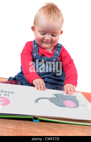 niedliche kleine Baby Mädchen ein großes Buch zu lesen, auf dem Boden sitzend Stockfoto