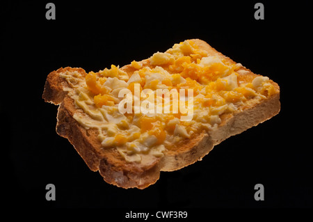 TOAST MIT VERSCHIEDENEN TOPPINGS SCHUSS AUF SCHWARZEM HINTERGRUND BOHNEN, MARMELADE, KÄSE, EI, ESSEN, SCHNELLES ESSEN, EINFACHES ESSEN, FAST FOOD, GUTES ESSEN. Stockfoto