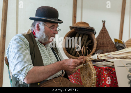 Mann in alten Trachten machen einen Bienenstock aus Peddigrohr auf die Fenland Land zeigen Cambridgeshire UK Stockfoto