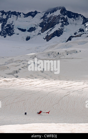 Eine kleine Gruppe von Touristen steht in der Nähe eines Helikopters, der Sehenswürdigkeiten in der Nähe des Franz-Josef-Gletschers auf der Südinsel Neuseelands ansieht. Stockfoto