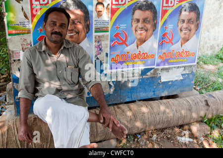 Indischer Mann posiert für ein Foto neben Wahlplakaten in Kerala Stockfoto