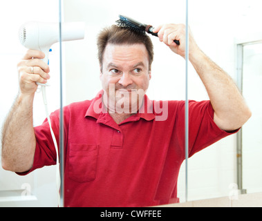 Reifer Mann föhnen Haare im Badezimmerspiegel. Stockfoto