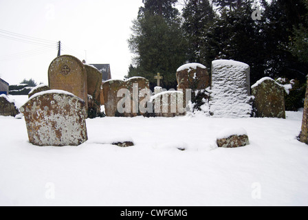 Schnee bedeckte Gräber im Kirchhof von All Saints Church in Harpole Stockfoto