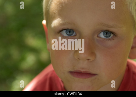 Porträt eines jungen Kindes blond blaue Augen Blick in die Kamera im Sommer draußen hautnah Stockfoto