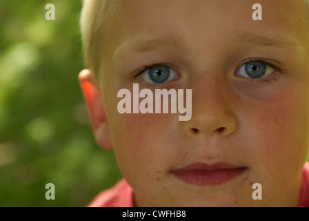 Porträt eines jungen Kindes blond blaue Augen Blick in die Kamera im Sommer draußen hautnah Stockfoto