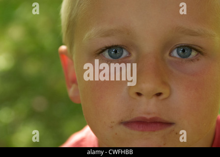 Porträt eines jungen Kindes blond blaue Augen Blick in die Kamera im Sommer draußen hautnah Stockfoto