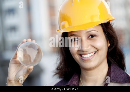 Lächelnde junge weibliche Bauingenieur hält eine Glaskugel Stockfoto