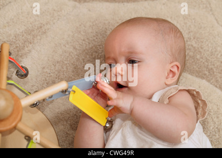 Ein 6 Monate altes Mädchen ein Baby-Decke auflegen und mit einem mobilen Spielen Stockfoto