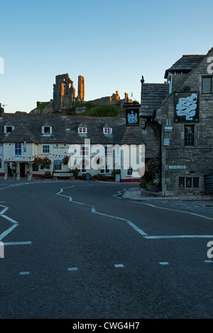 Corfe Castle durch die aufgehende Sonne beleuchtet. Die Greyhound Inn und Marocco Arme Corfe Dorf Dorset-England Stockfoto