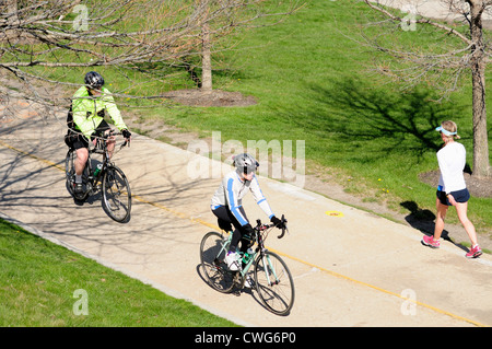 Übung-Radfahrer und ein einsamer Wanderer nutzen einen Radweg im Grant Park in einem Frühlingsmorgen. USA-Illinois-Chicago Stockfoto