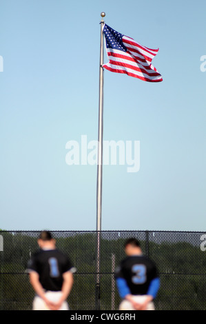 Baseball zwei Spieler ehren die Flagge während des Spiels der Star Spangled Banner vor dem Start eines High School-Spiel. USA. Stockfoto