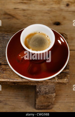 Espresso-Kaffeemaschine in dicken braunen Tasse auf alten Holzbank Stockfoto