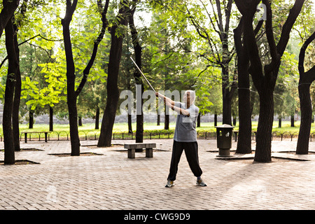 Ein älterer Mann chinesische Praktiken Martial Arts mit seinem Rohrstock Morgenspaziergang im Tempel des Himmels Park im Sommer in Bei Stockfoto