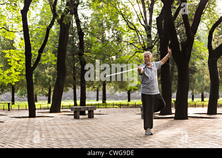 Ein älterer Mann chinesische Praktiken Martial Arts mit seinem Rohrstock Morgenspaziergang im Tempel des Himmels Park im Sommer in Bei Stockfoto