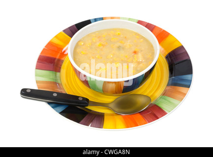 Eine große Portion heiße alte altmodische Maissuppe in Schüssel auf einer hellen Schale mit Suppenlöffel vorne auf einem weißen Hintergrund. Stockfoto