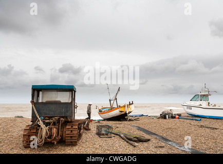 Ein einsamer Mann zu Fuß entlang der Kiesstrand am Aldeborough unter den Fischerbooten vor einem grauen Himmel Stockfoto
