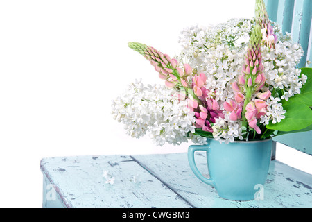 Anordnung der Wildblumen auf einem rustikalen hellen blauen Stuhl isoliert auf weiss Stockfoto