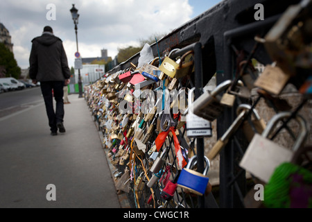 Ein Mann geht vorbei an Tausenden von Vorhängeschlössern auf Pont des Arts über den Fluss Seine, Paris Stockfoto