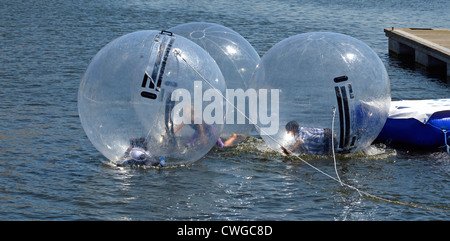 Kinder spielen im Inneren angebunden aufblasbare Bubbles auf dem Dock Wasser Aqua Kugeln Anlage mit Tageseltern (aus schießen) in Anwesenheit Stockfoto