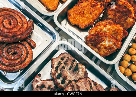 Wurst, Schinken, Schnitzel und Kartoffeln auf Tellern für den Verzehr ausgesetzt Stockfoto