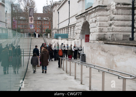 Menschen Schlange, um in den Seiteneingang der Tate Britain spiegelt sich in einer klaren Fußgänger Barriere zu bekommen Stockfoto