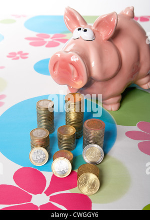 Sparschwein mit Muenzstapeln auf gemusterten Hintergrund Stockfoto