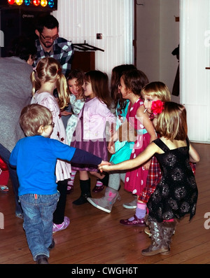 Kinder tanzen mit den Eltern in einer Diskothek tun Hokey Cokey im fünften Geburtstag feiern England Stockfoto