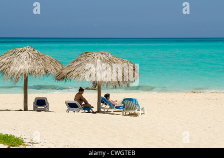 Paar am Strandliegen und Sonnenschirme im Sol Cayo Santa Maria Resort, Cayo Santa Maria, Kuba. Stockfoto