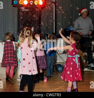 Kinder tanzen mit Luftblasen in einer Diskothek in einer fünften Geburtstag feiern England Stockfoto