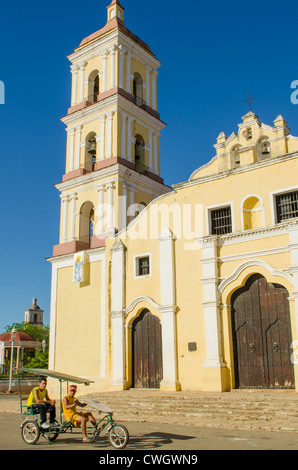 Leute Reiten Dreirad Taxi vor der Kirche Iglesia Mayor de San Juan Bautista in Remedios, Kuba. Stockfoto