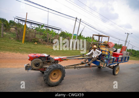 Horizontale Sicht auf eine typische Straßenszene in Kambodscha mit einem Landwirt fahren eines langen chassised Traktor, Cgo Yong oder Roboter-Kuh. Stockfoto