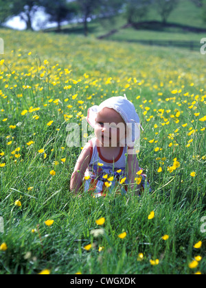 Kleinkind sitzen auf einer Wiese mit gelben Blumen Lächeln. Stockfoto