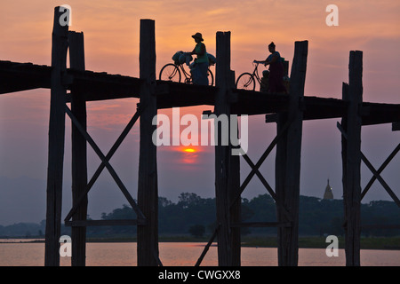 Die BURMESISCHEN Verwendung das Teakholz Brücke U KLANGKUNST um zu pendeln über den Taungthaman-See bei Sonnenaufgang - AMARAPURA, MYANMAR Stockfoto