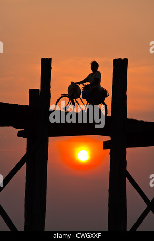 Die BURMESISCHEN Verwendung das Teakholz Brücke U KLANGKUNST um zu pendeln über den Taungthaman-See bei Sonnenaufgang - AMARAPURA, MYANMAR Stockfoto