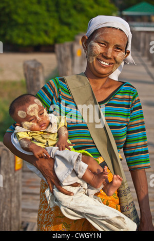 Eine BURMESISCHE Mutter mit Baby nutzt das Teakholz U KLANGKUNST Brücke Pendeln über den Taungthaman-See - AMARAPURA, MYANMAR Stockfoto