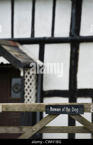 Hüten Sie sich vor dem Hund Zeichen auf ein Tor vor einer alten schwarz / weiß gerahmte Holzhaus. Herefordshire. England Stockfoto