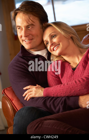 Applying paar im Chat auf Sofa im Chalet mit Winter-Blick Stockfoto