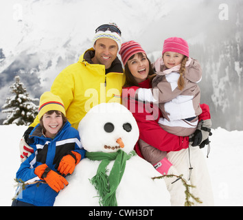 Familie Gebäude Schneemann auf Ski-Urlaub In Bergen Stockfoto